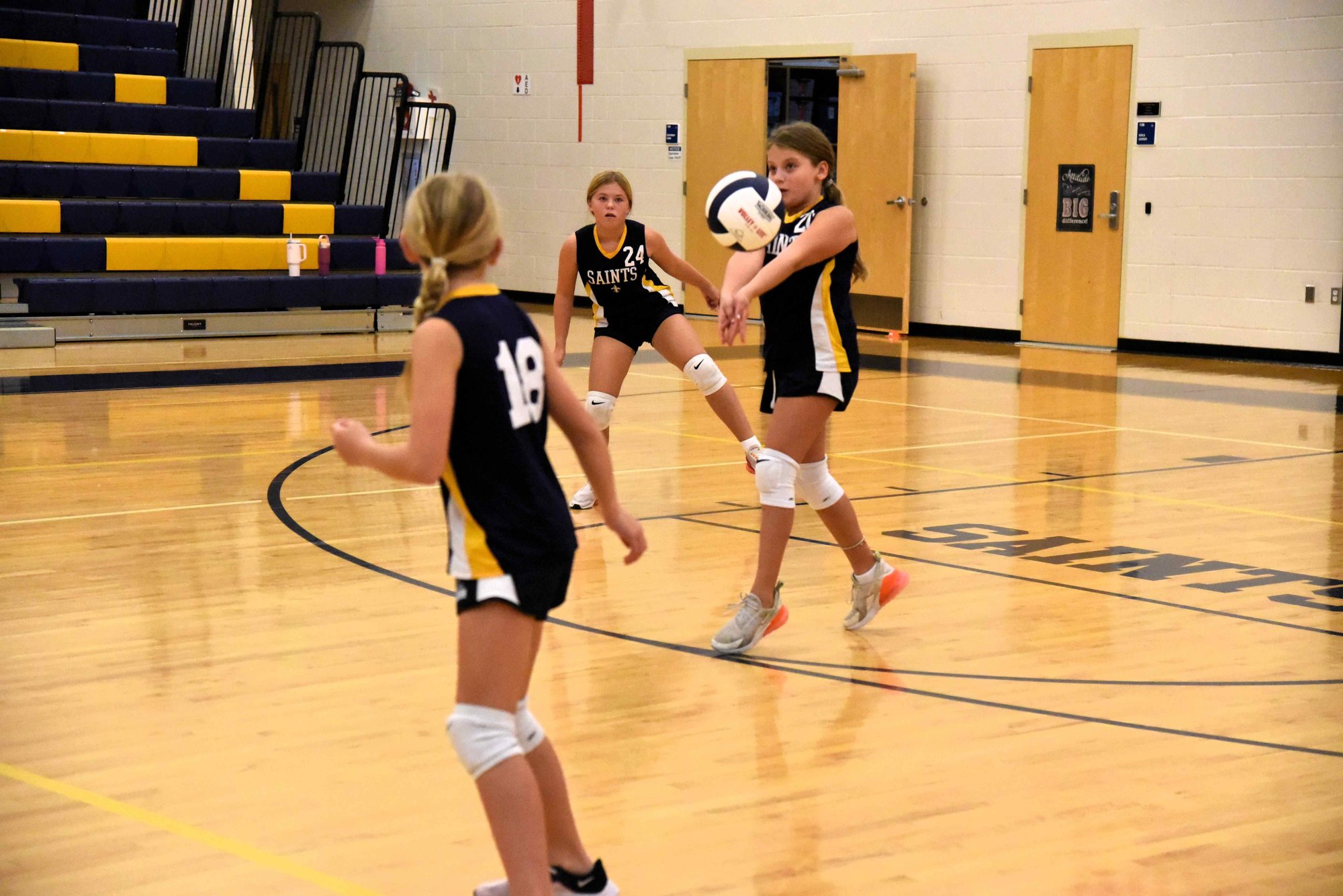 Three female students playing volleyball.