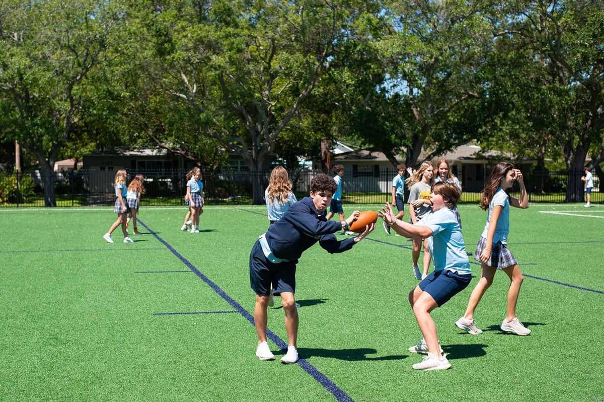 Student playing football on field during physical education class.