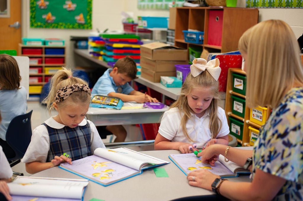 A teacher helping two students with an art project.