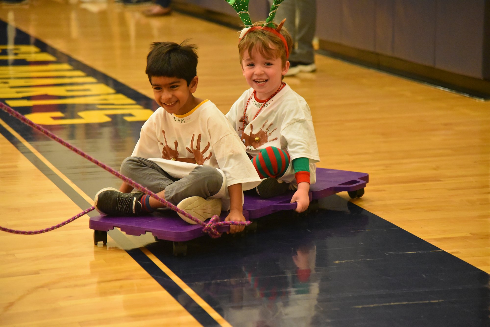 Two students playing on a scooter board.