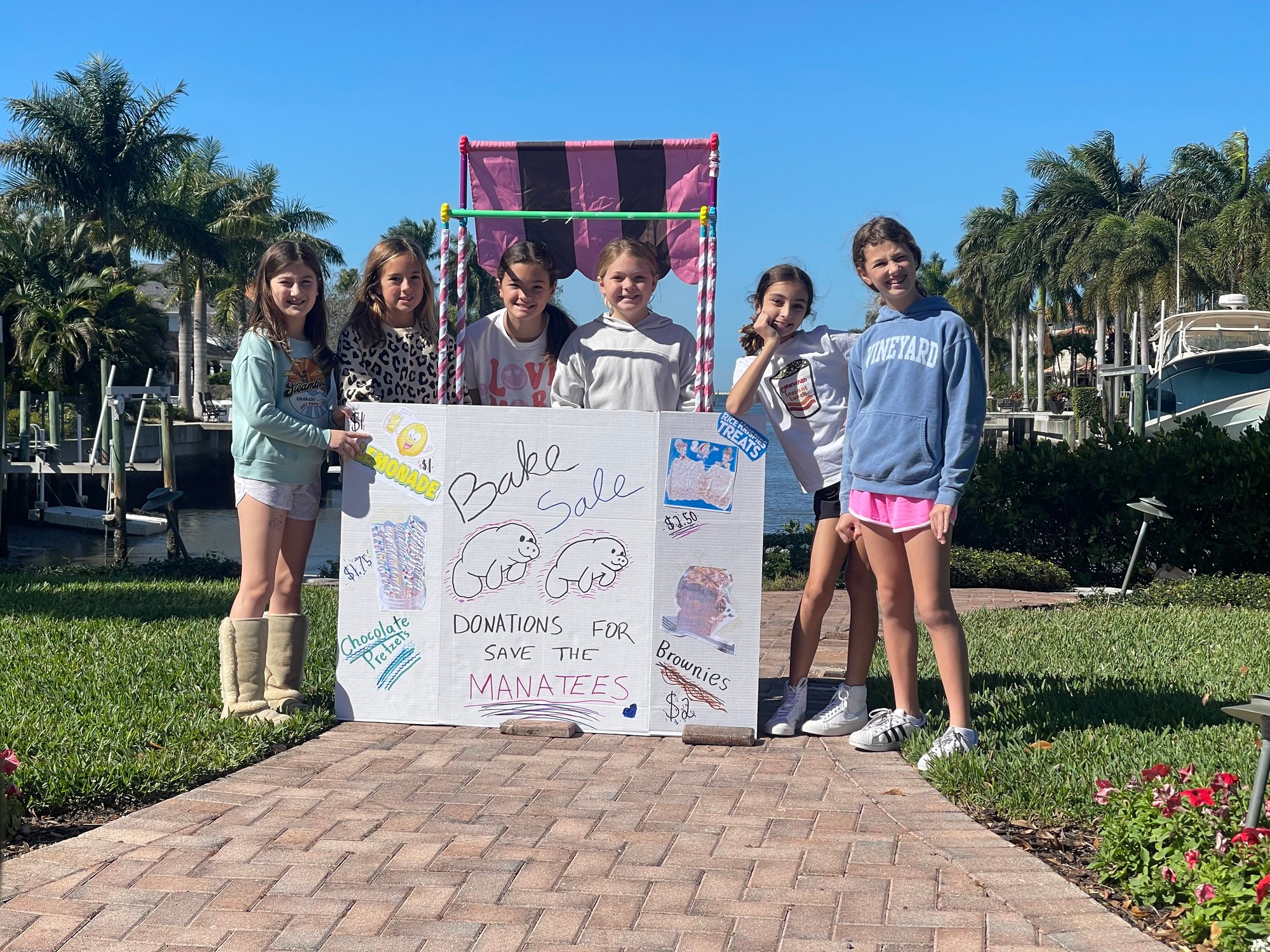 A group of students outside in a stand for a bake sale.