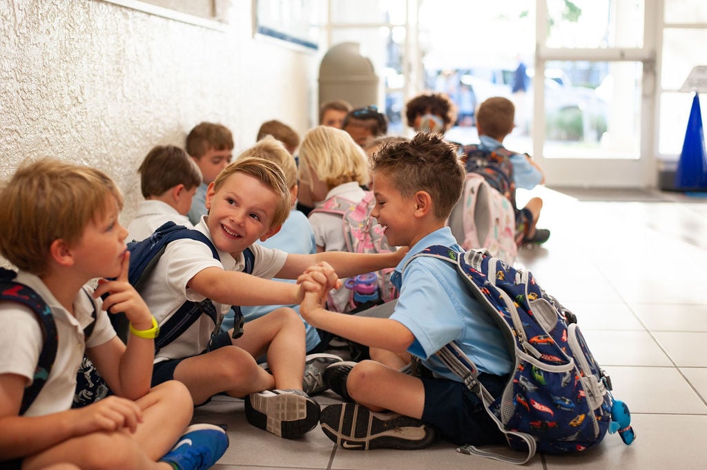 Boys sitting criss cross in the hallway.