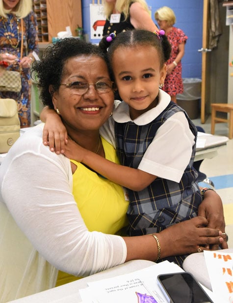 Student sitting with her grandmother in classroom.