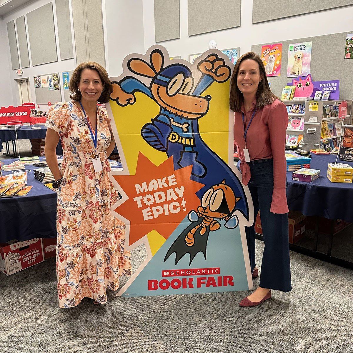 Two teachers standing in front of a character billboard saying "Make Today Epic"