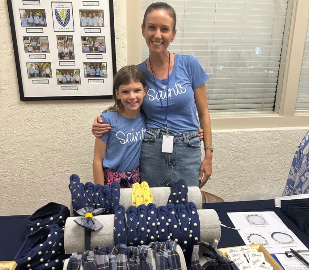 Mom and daughter selling St. Mary's headbands for Parents' Association.