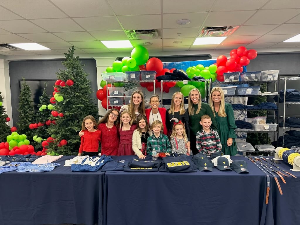 A group of parents and students standing behind a table full of St. Mary's merchandise.