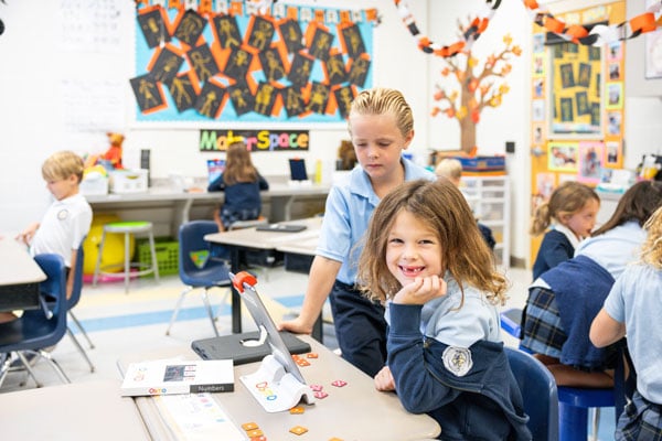 A female student smiling while doing an activity on an iPad.