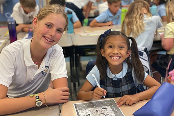 An older and younger student in class together smiling.