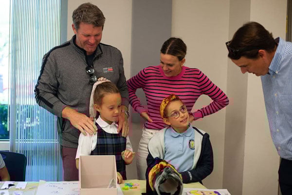 Two students and three teachers interacting with science projects.