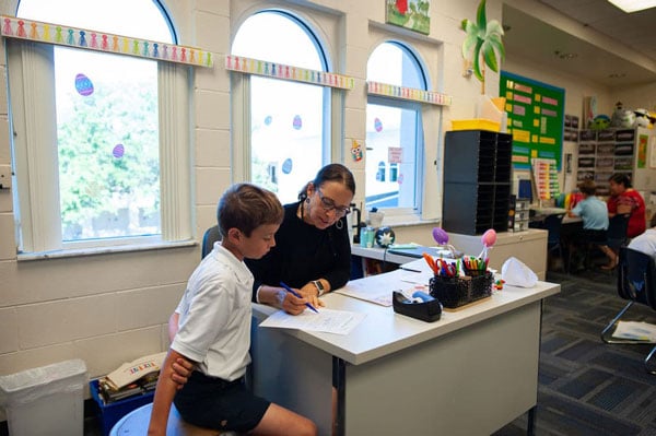 A teacher assisting a student with their work in the enrichment center.