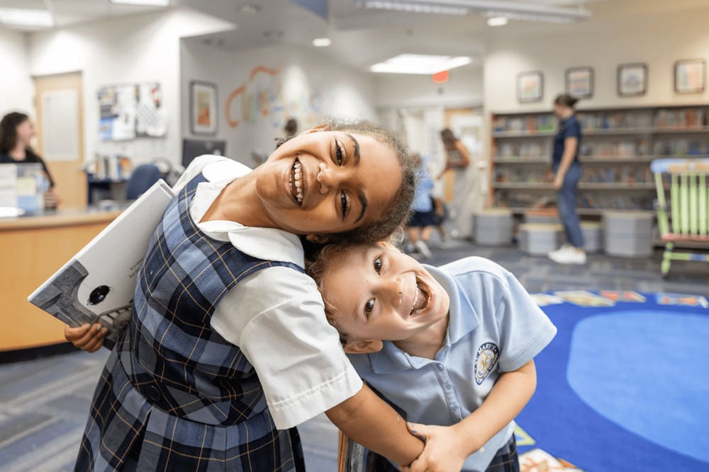 Two children inside the library smiling.