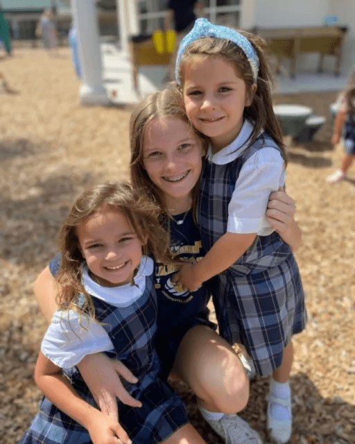 Three female students smiling and hugging.