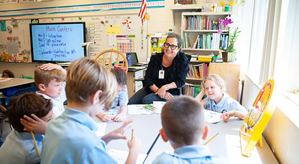 Smiling teacher in classroom with students.