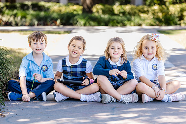 Students sitting on ground outside smiling.