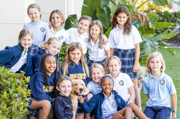 A group of smiling students standing outside with dog..